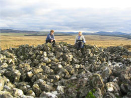 Two volunteers sit on top of somr pf the cairns within the group
