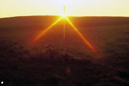 Ranging rod showing mid summer sunrise above stone circle